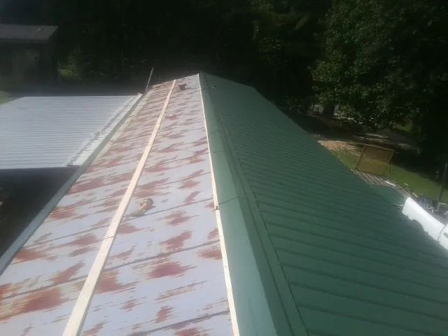 Old rusted panels beside newly installed green metal roofing — Wind Damage Roof Repair by Roofing Brothers in Spring Green