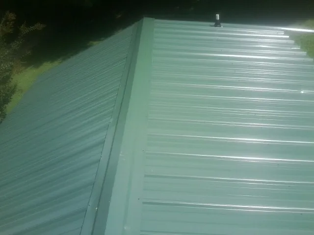 New green metal panels meeting at the ridge of a roof — Flat Roof Repair work by our crew in Spring Green