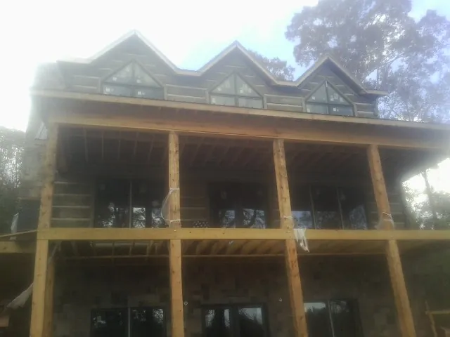 Dormers and porch framing on a large log home under construction — Roof Coating work by our crew in Spring Green