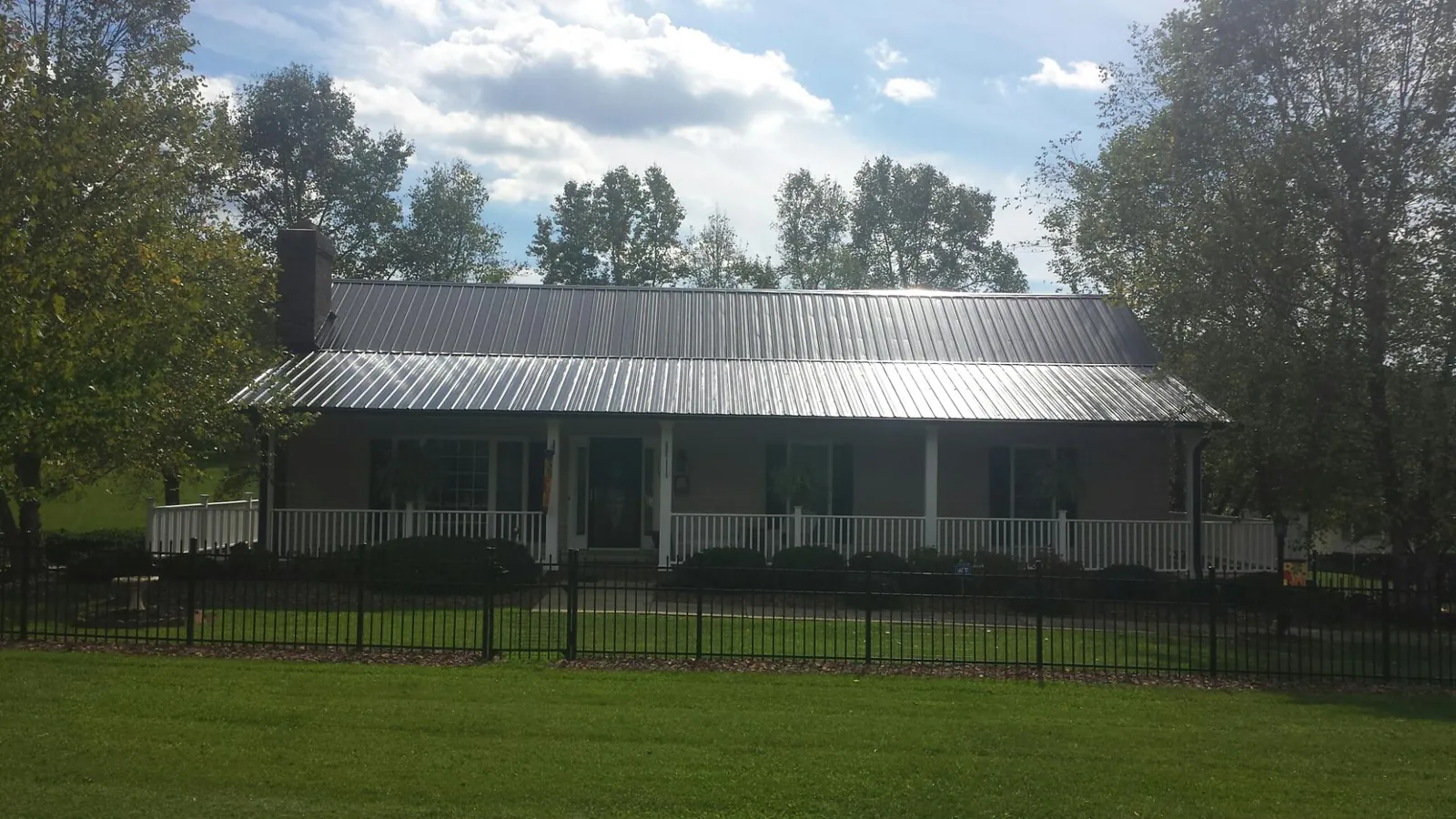 Gray metal roof on a brick ranch with a full width front porch — Gutter Guard Installation work by our crew in Spring Green