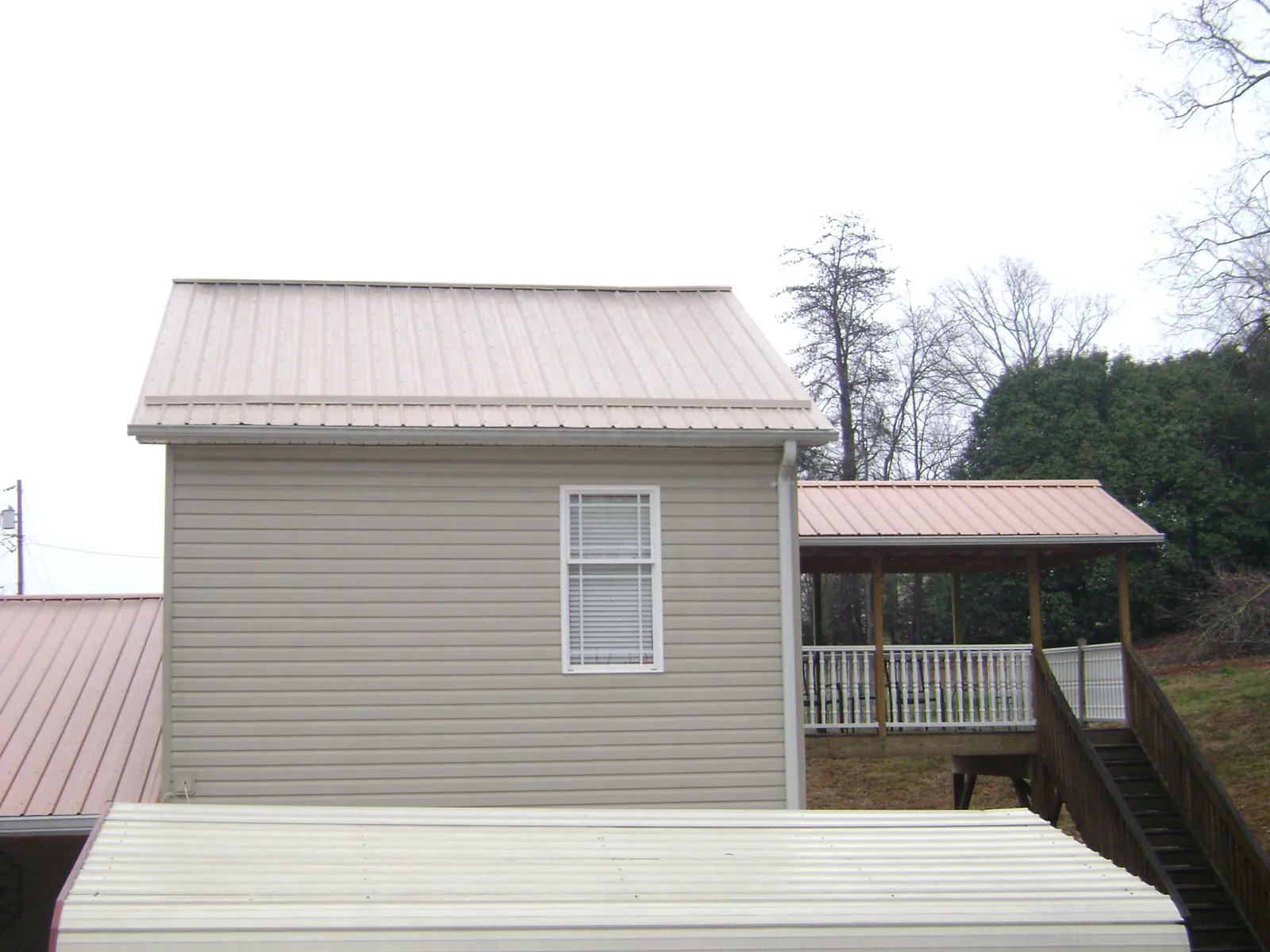 Tan metal roofs on a two story addition and attached porch, from a Roof Replacement job in Spring Green