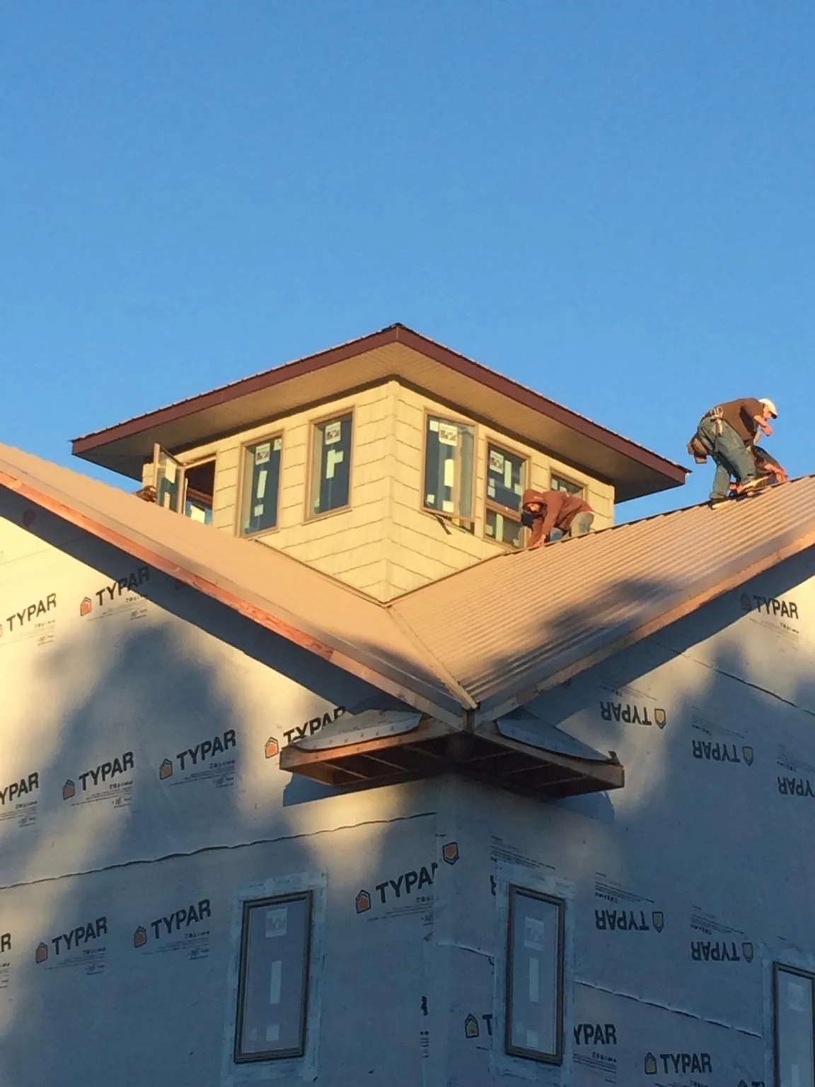 Roofers working around a rooftop cupola on a new metal roof at sunset — Roof Waterproofing in Spring Green by Roofing Brothers